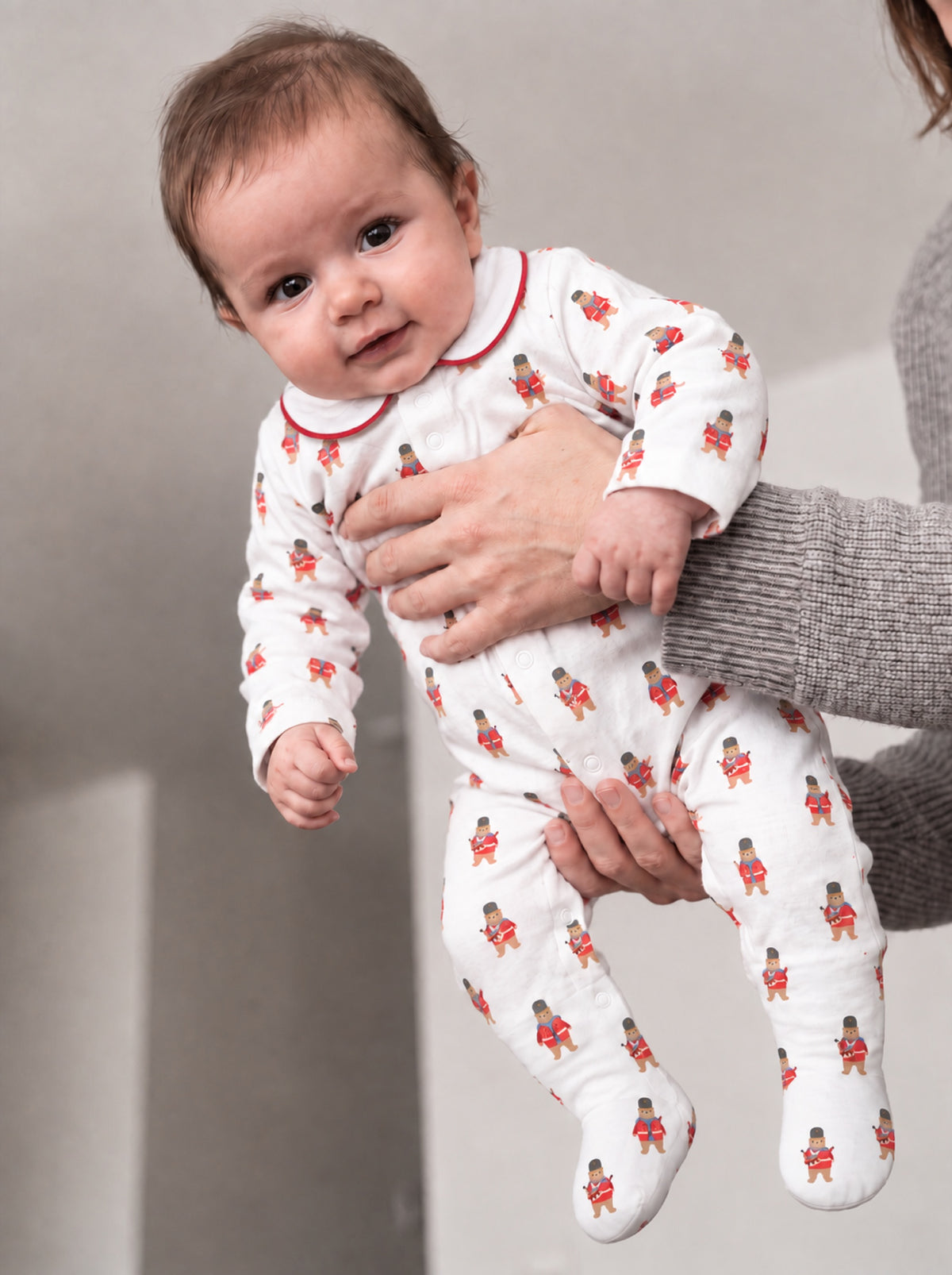 Baby held up in the ivory guard bear sleepsuit, showing the front poppers