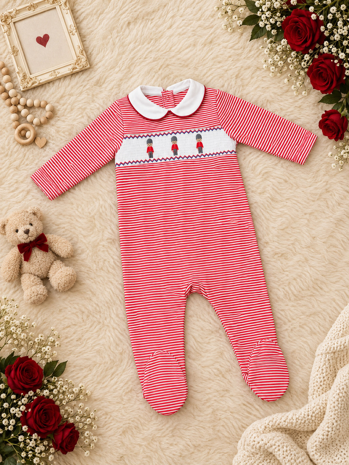 Red-stripe footed sleepsuit with smocked toy-soldier panel, front, laid flat