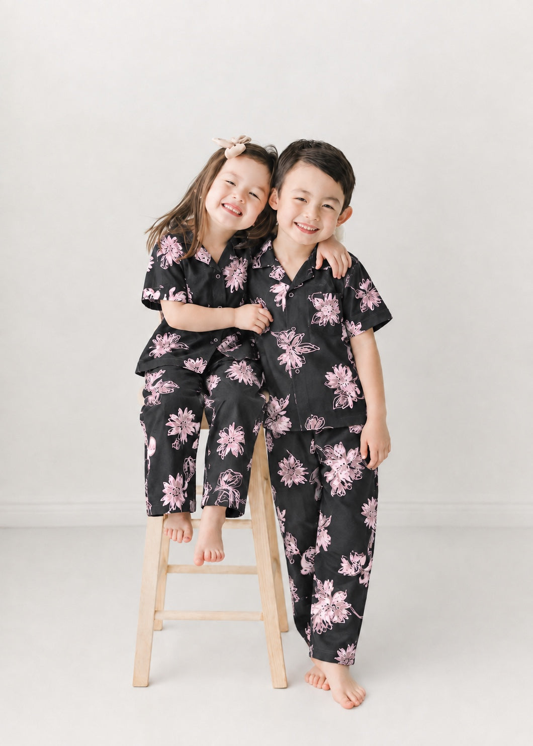 Two children smiling in the black and light pink floral shirt and trousers set