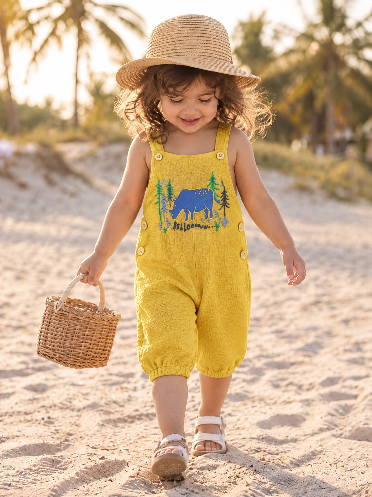 Toddler walking on the beach in the Forest Bellow dungarees