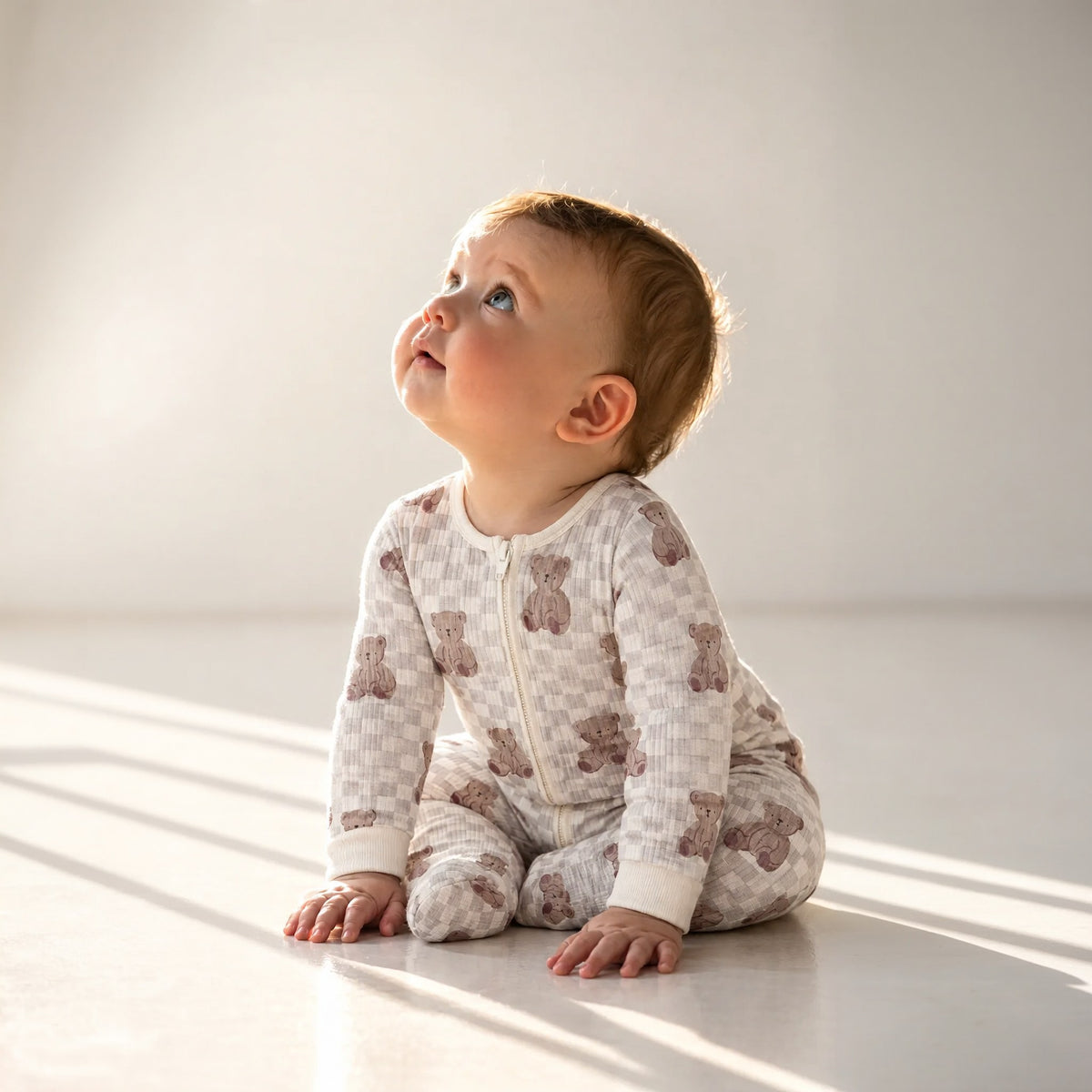 Baby sitting in the bear checkerboard sleepsuit, front view