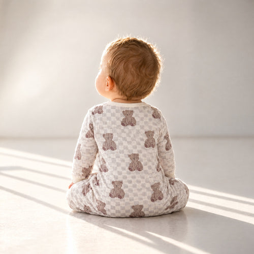 Baby sitting in the bear checkerboard sleepsuit, back view