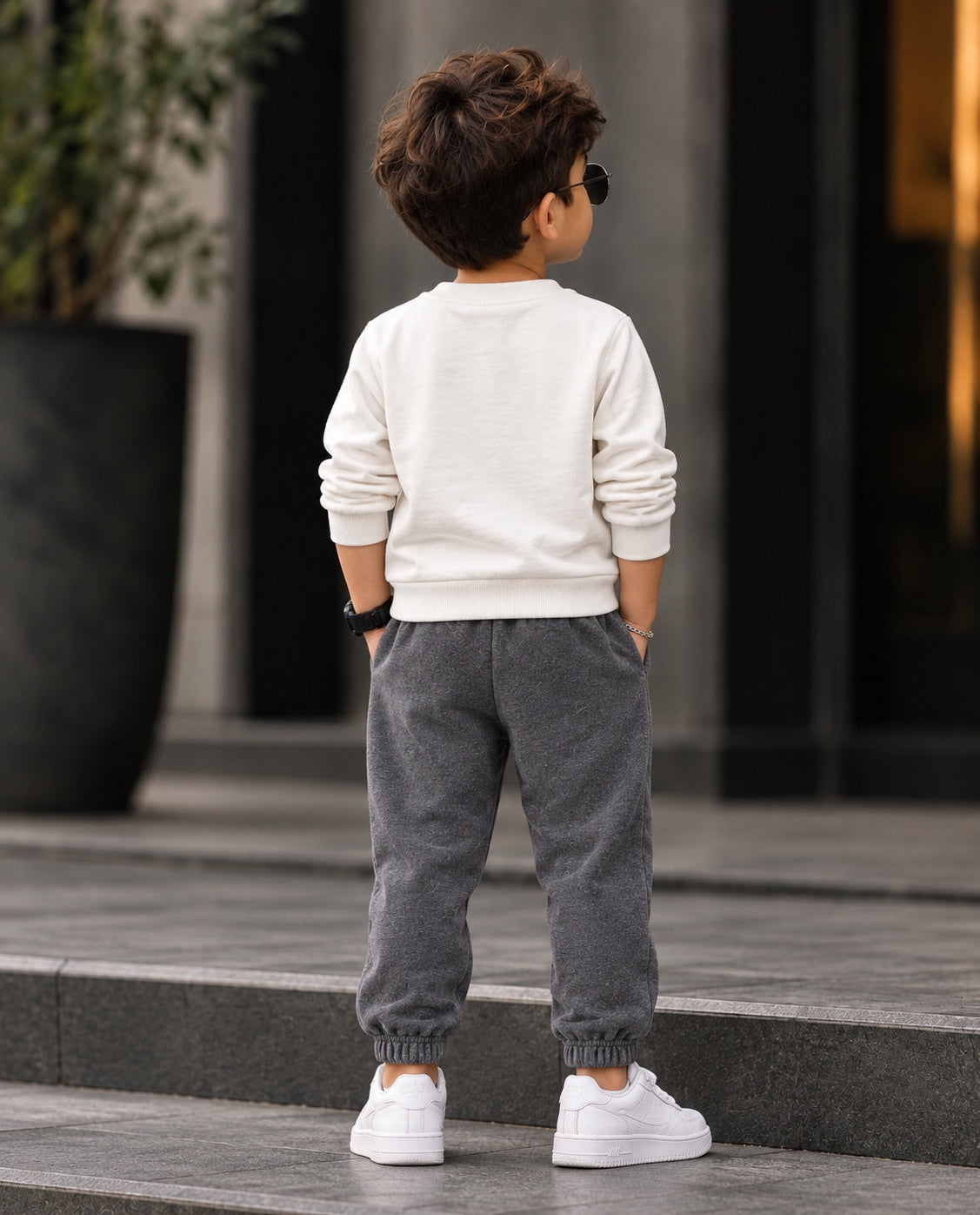 Boy standing outdoors in the van sweatshirt and charcoal joggers, back view